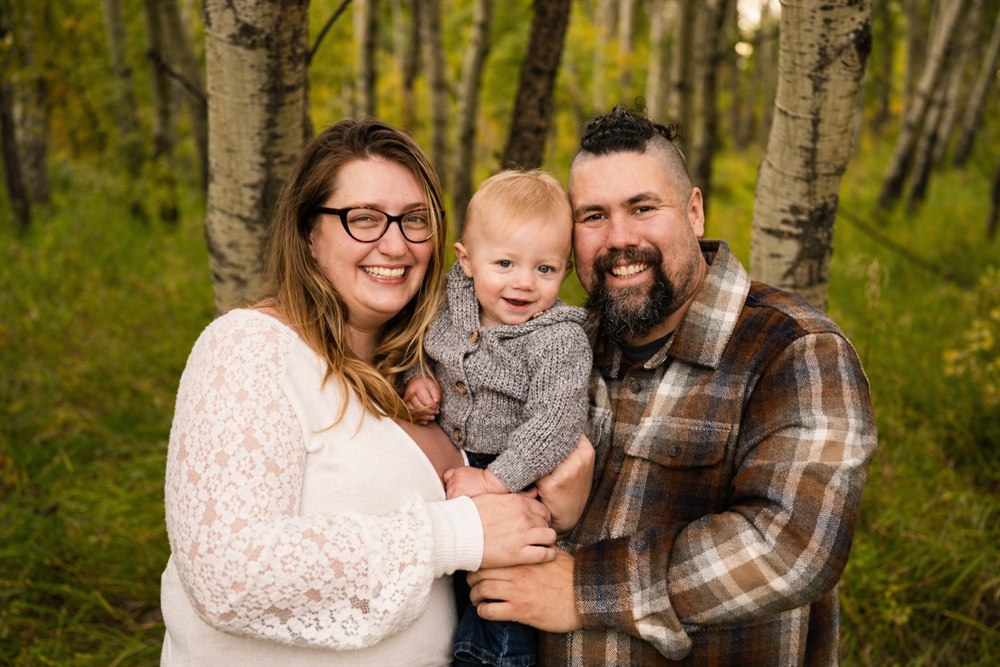 Family portrait of Kind Behaviour co-founders Jessica Bist and Jason Lefebvre with their child outdoors.
